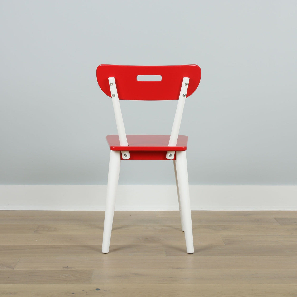 Red and white wooden chair with modern design against light gray wall.