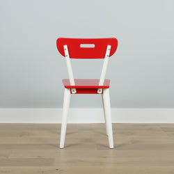 Red and white wooden chair with modern design against light gray wall.