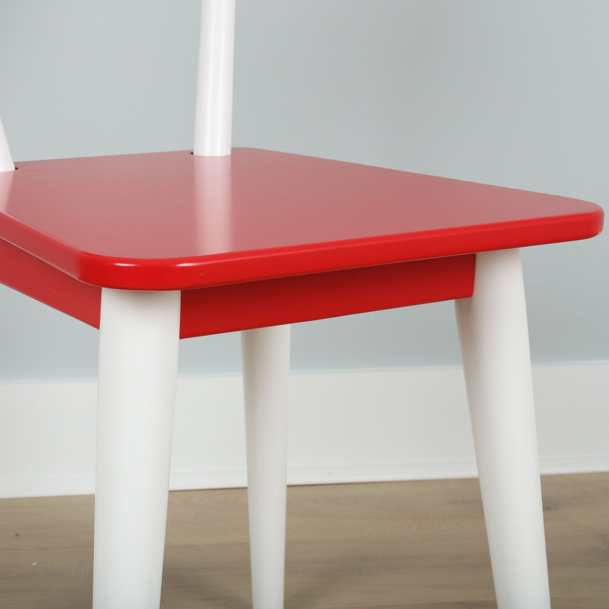 Red and white modern chair with minimalist design on wooden floor.