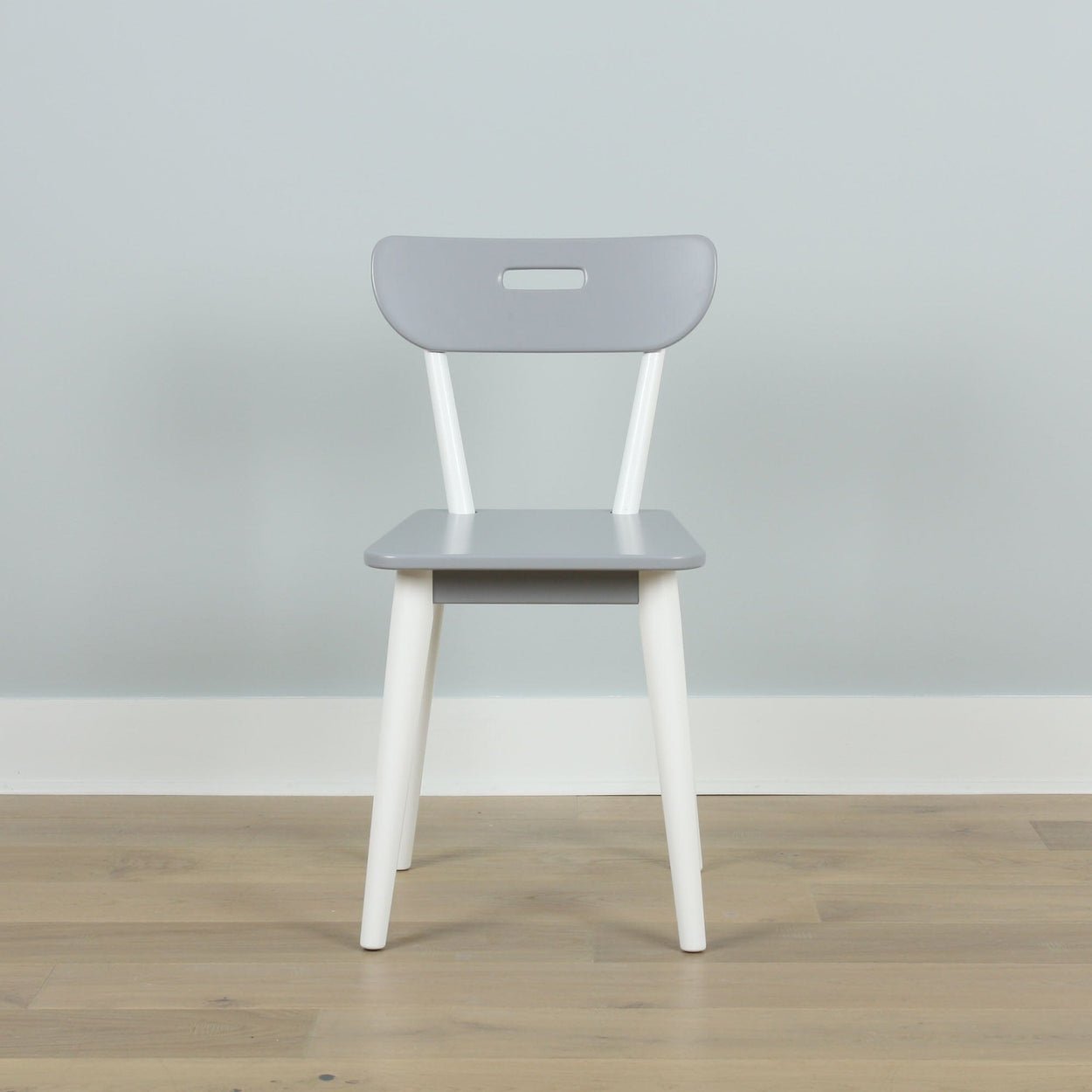 Gray and white minimalist chair on wooden floor against light gray wall, modern interior design.