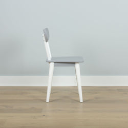 Modern gray and white wooden chair on a light wood floor against a pale blue wall.