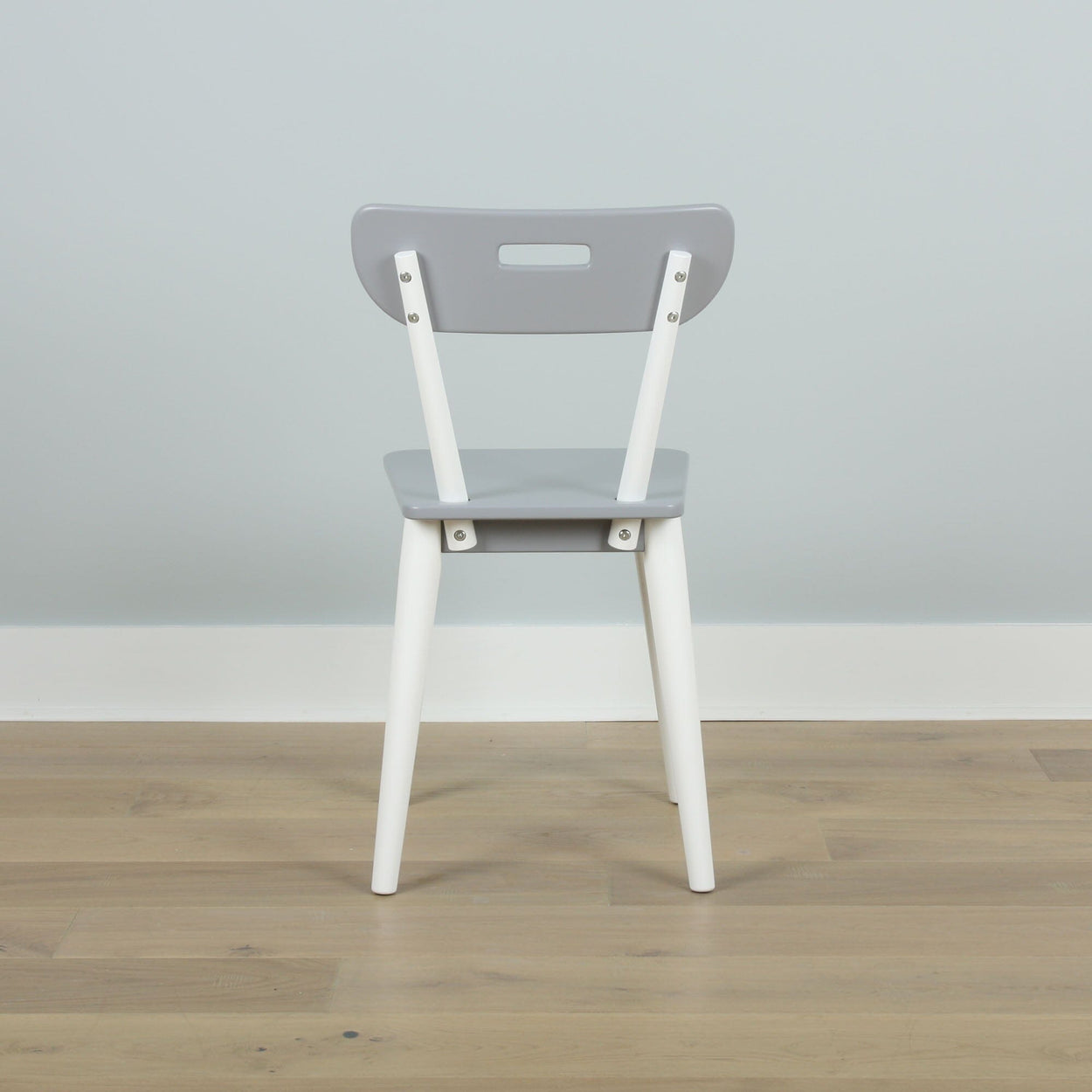 Gray and white modern chair with a sleek design placed on a wooden floor against a light gray wall.