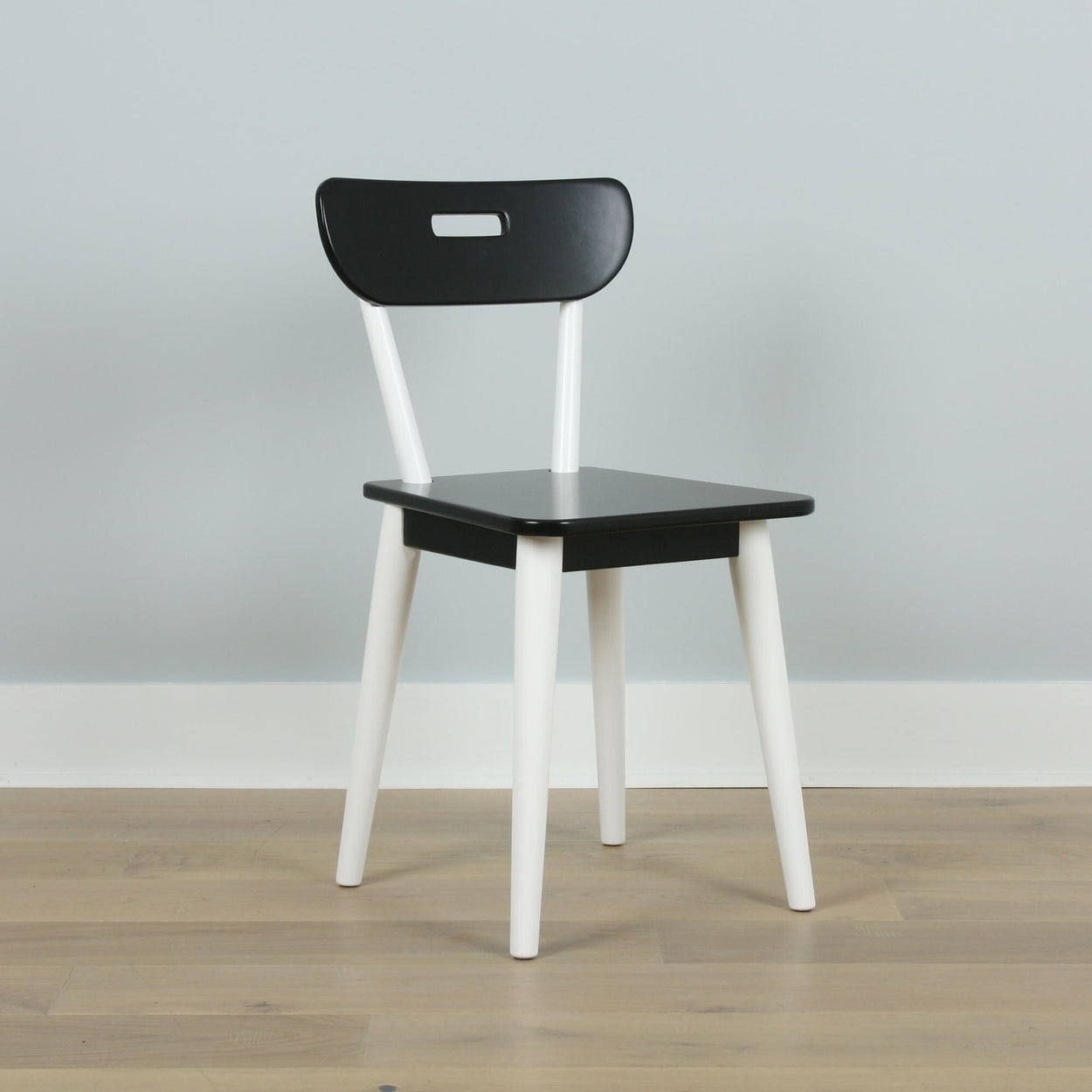 Modern black and white wooden chair on a light wooden floor.