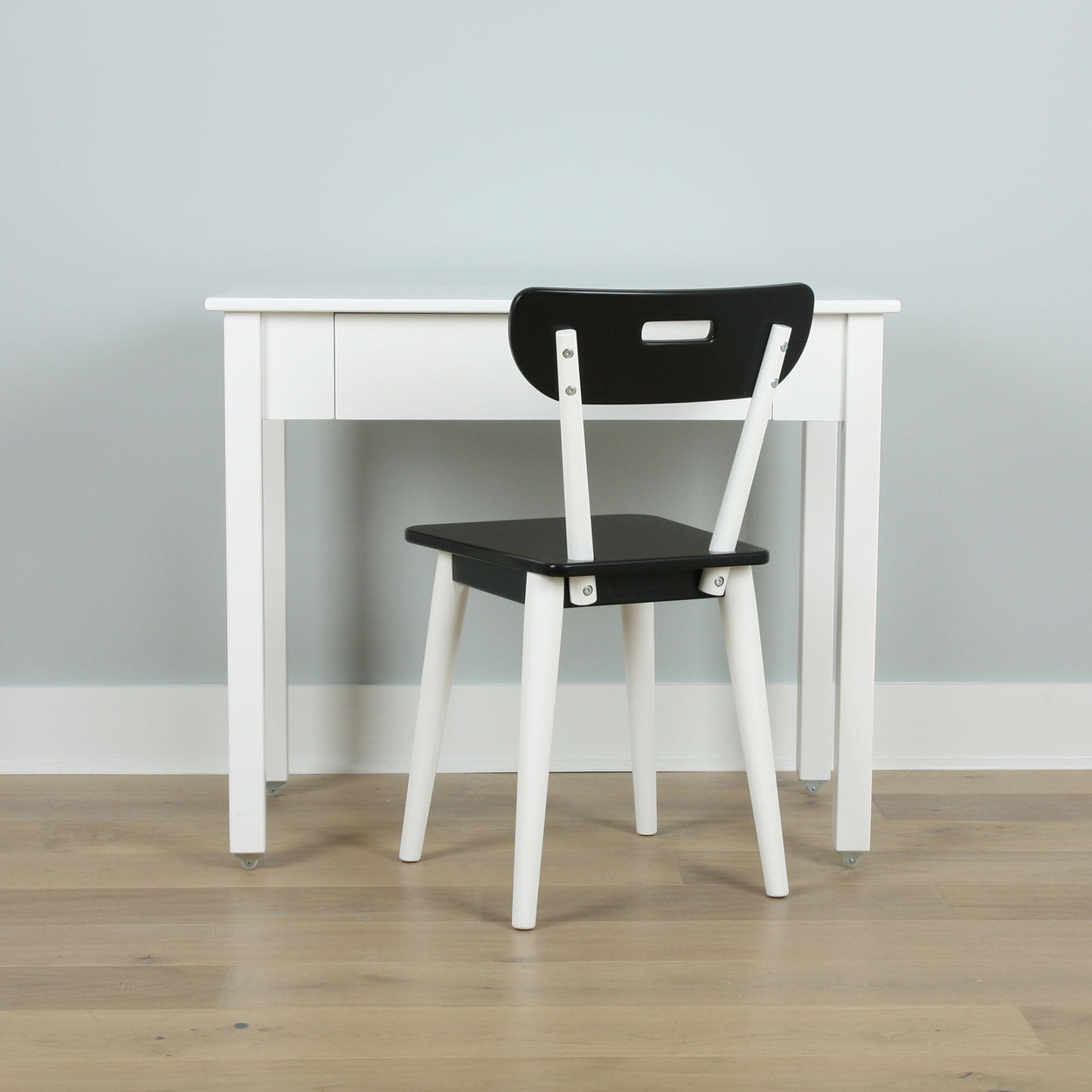 Minimalist black and white desk and chair set on wooden floor.