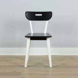 Black and white modern chair on wooden floor against a gray wall.