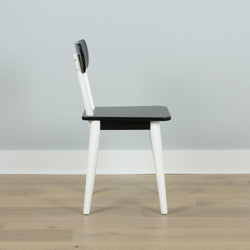 Modern black and white wooden chair on light wood floor.