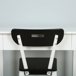 Back view of a modern black and white chair placed in front of a minimalist white desk.