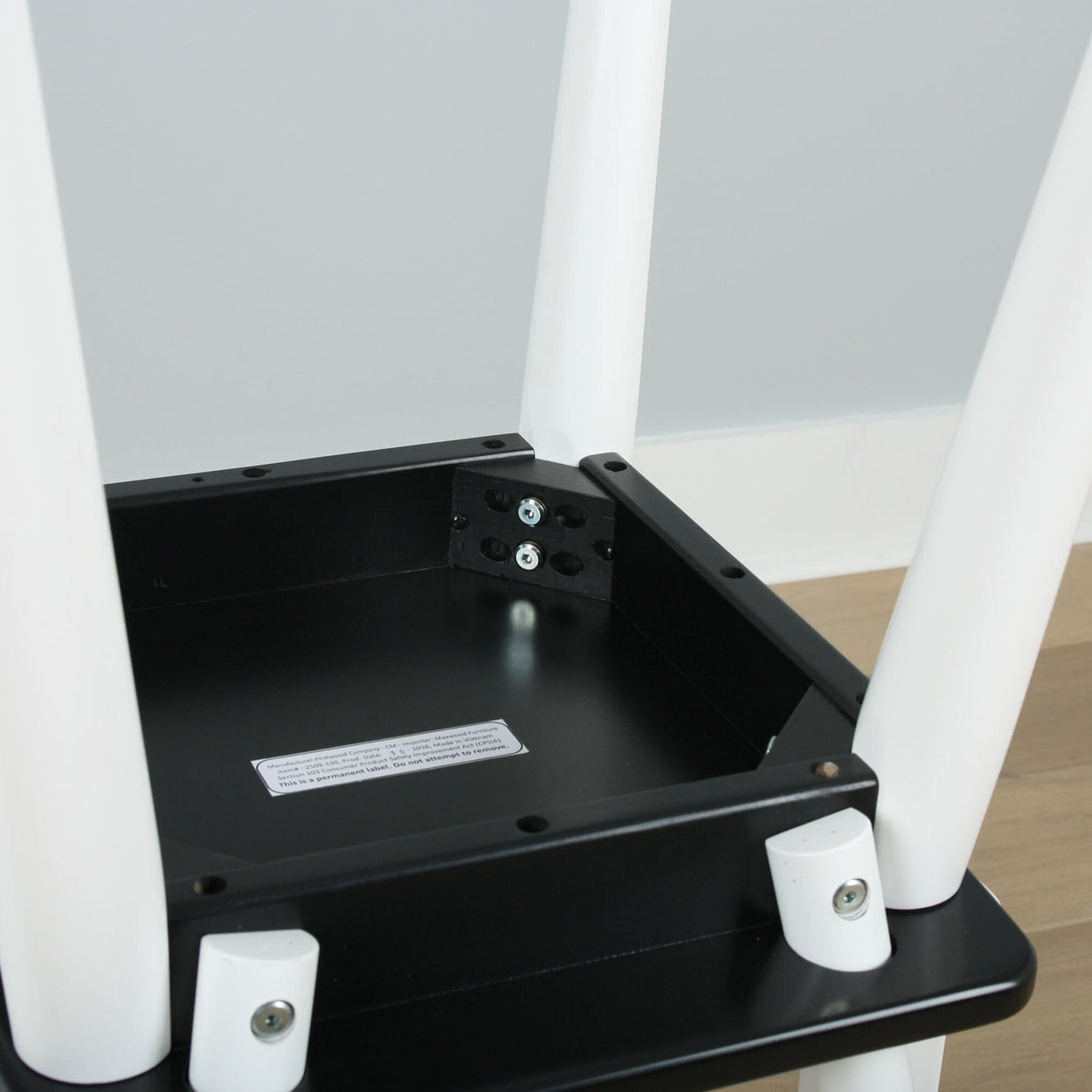 Close-up view of a black and white table leg assembly, showing screws and fittings for sturdy support.