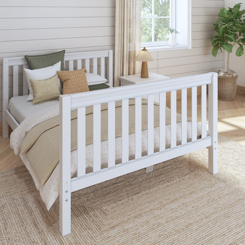 White wooden baby crib in a modern farmhouse nursery with neutral bedding, woven pillows, bedside lamp, shiplap walls, fiddle leaf fig plant and jute rug