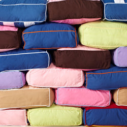 Stack of colorful, rectangular pillows in various hues, including blue, pink, and green, perfect for home décor.