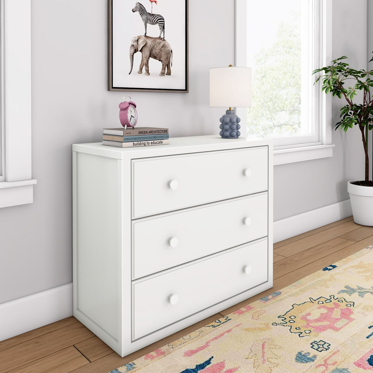 White three-drawer dresser in modern bedroom interior with decorative lamp and artwork.
