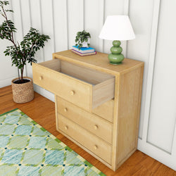 Wooden dresser with open drawer, table lamp, books, and potted plant in stylish bedroom.