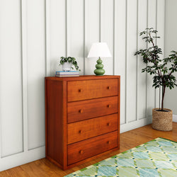 Wooden dresser with lamp and plants in modern room with wood flooring and rug.