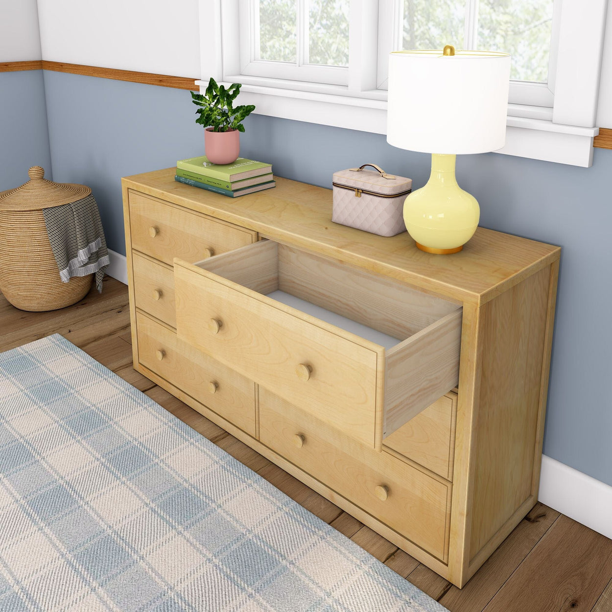 Wooden dresser with open drawer in a cozy room, featuring a lamp, potted plant, and decorative items on top.