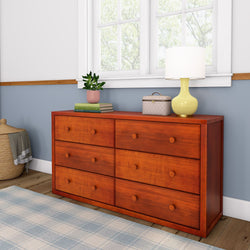 Wooden dresser with drawers in a modern bedroom setting, featuring a lamp, plant, and decorative box on top.