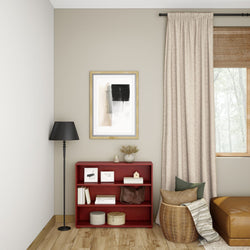 Minimalist living room interior with red bookshelf, black floor lamp, abstract wall art, and neutral decor elements.