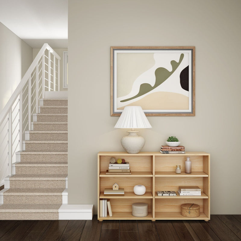 Modern home interior with abstract wall art, wooden shelf, decorative lamp, and carpeted staircase.