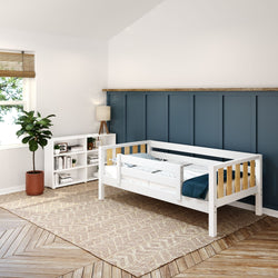 Toddler bed with side rails in a modern nursery room featuring a blue accent wall, wooden floor, and cozy decor.