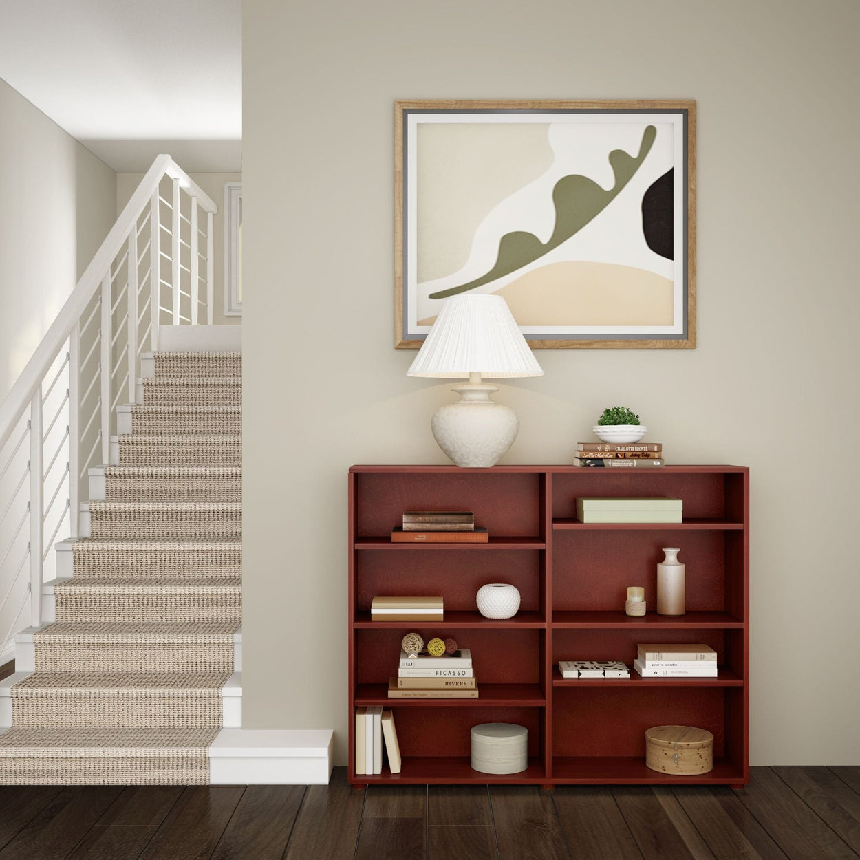 Modern minimalist living room corner with staircase, wooden bookshelf, abstract art, and table lamp.