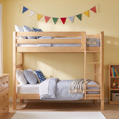 A light natural wood children's loft bed with an attached desk and storage drawers, shown in a bright, modern bedroom setting.