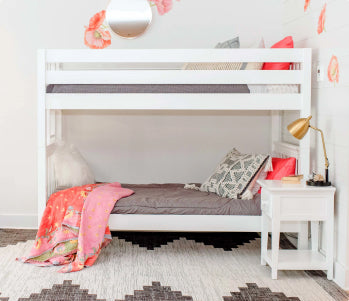 Modern kids' bedroom with white twin over-twin bunk beds featuring central staircase and built-in drawers, navy blue and white bedding, yellow walls, large windows, beige area rug and potted plant.
