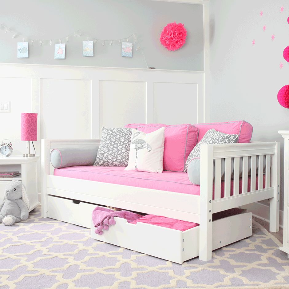Children's bedroom with white daybed featuring pink cushions and storage drawers, ideal for chic and functional decor.