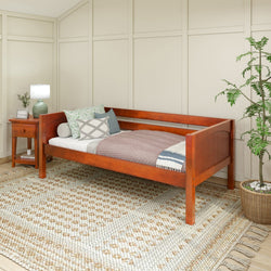 Wooden daybed with pillows and side table in a cozy room.