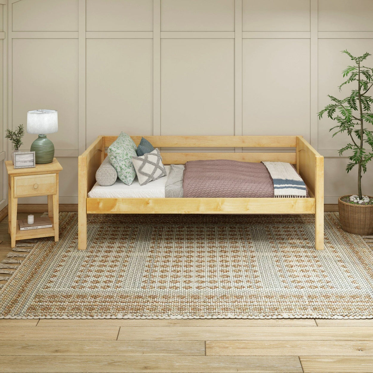Wooden daybed with cozy pillows and mauve blanket in modern bedroom setting, next to a nightstand and potted plant.