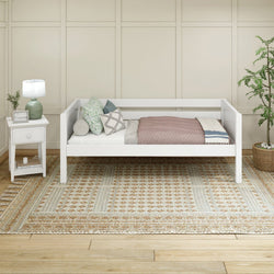 Minimalist white daybed in cozy bedroom with decorative pillows, stylish nightstand, and textured area rug.