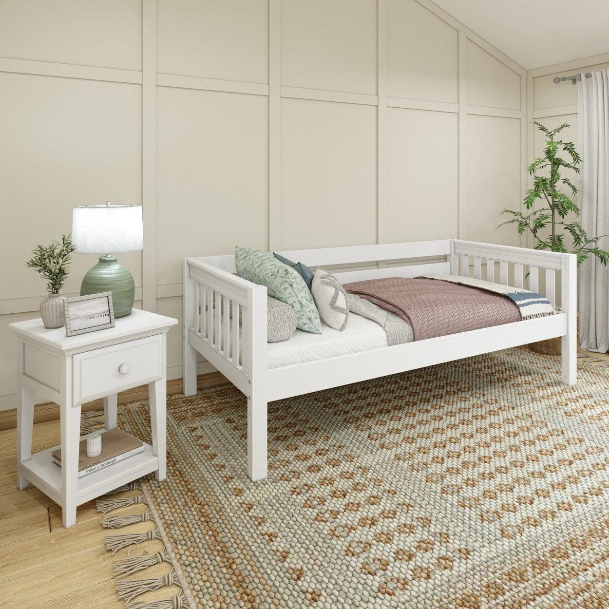 White daybed in a cozy bedroom with wooden nightstand, patterned area rug, and decorative pillows.