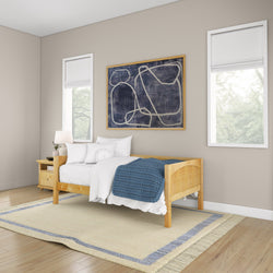 Cozy bedroom with minimalist wooden bed, white bedding, blue blanket, modern abstract wall art, and natural light.