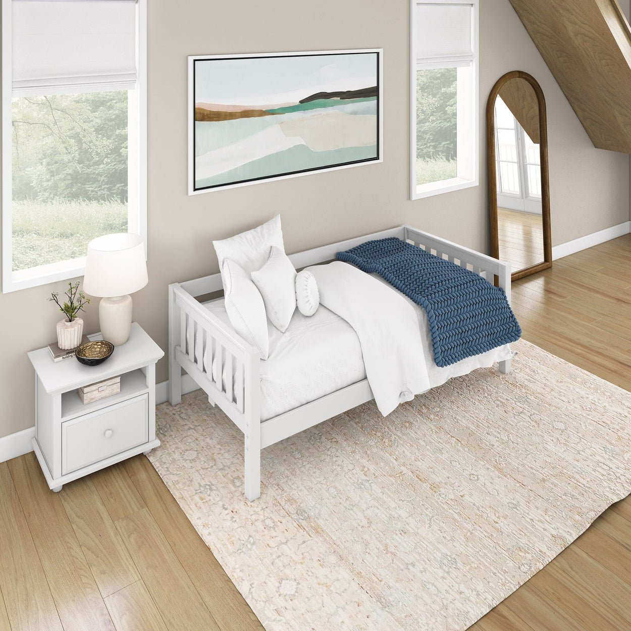 Modern attic bedroom with white daybed, blue throw blanket, and decorative mirror.