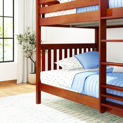 Wooden bunk bed with blue bedding in a bright, airy bedroom with a potted plant and light-filled window.