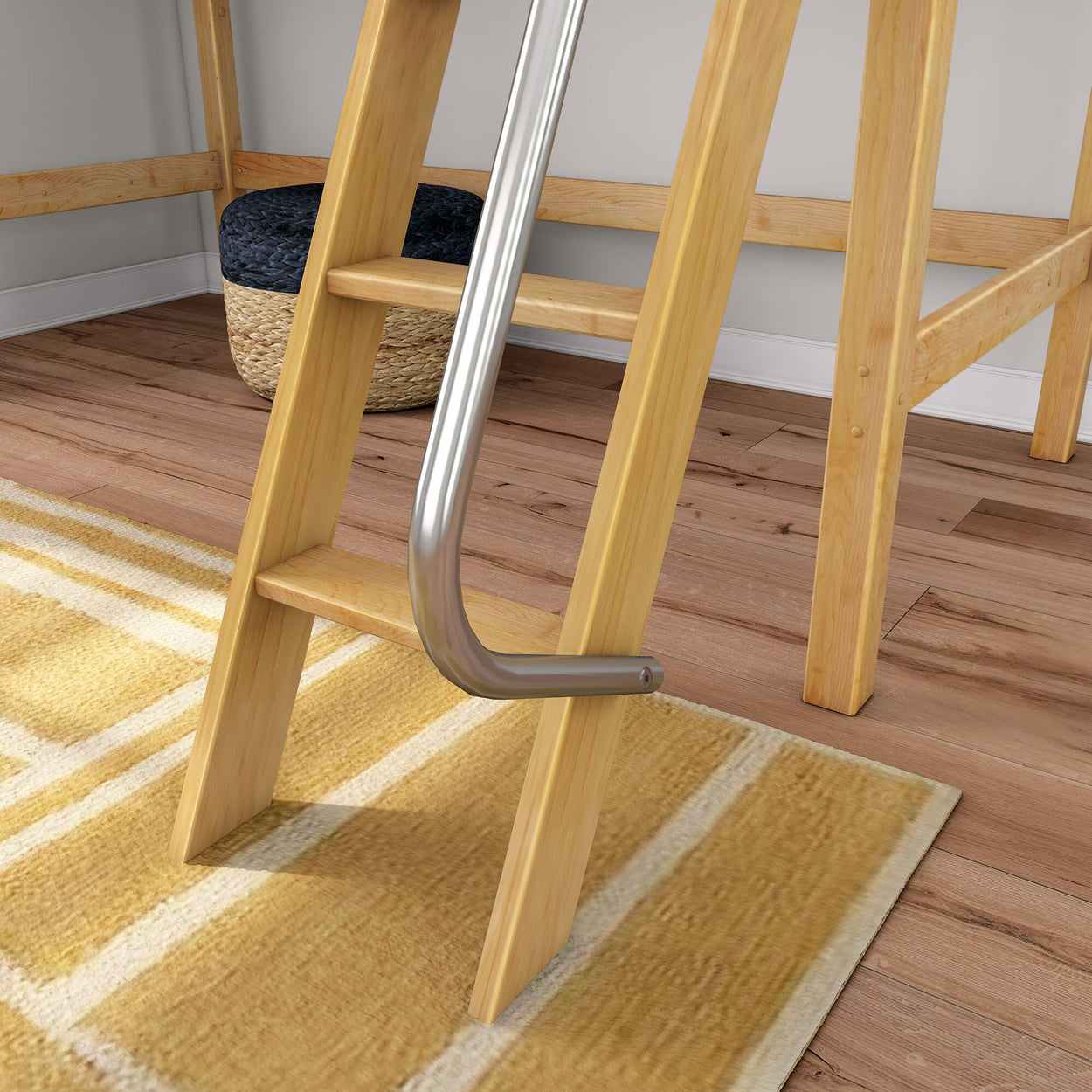 Wooden loft bed ladder with silver metal safety rail attached, set on hardwood floor beside yellow striped area rug and woven storage basket