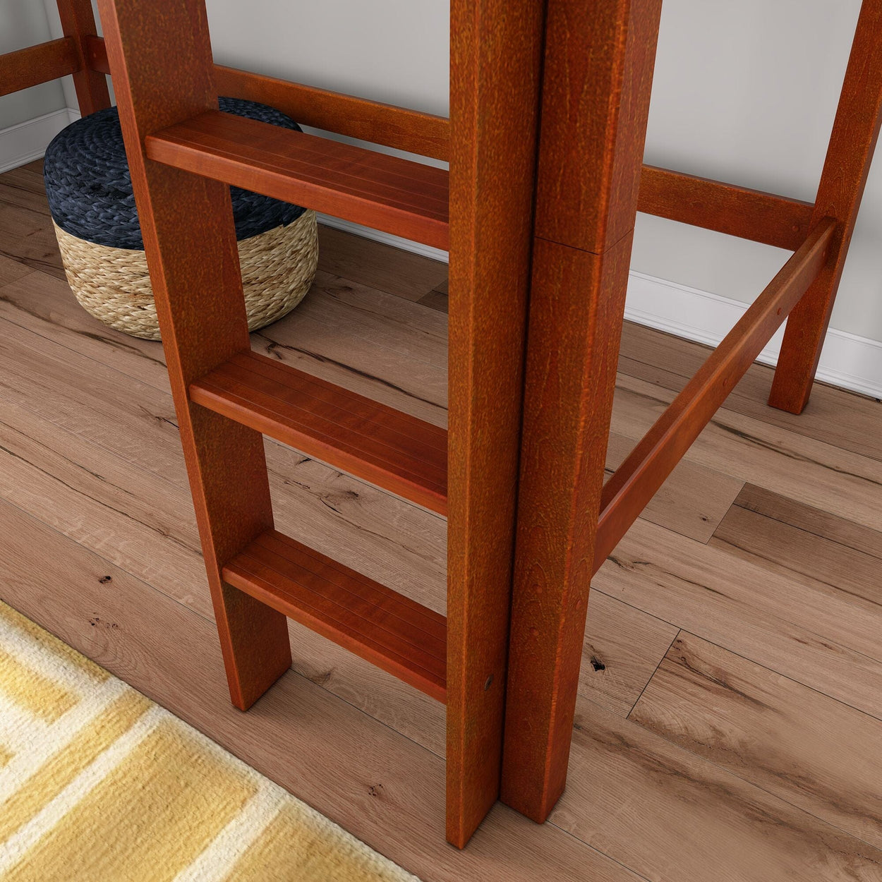 Close-up of a reddish wooden loft bed ladder on light hardwood floor with woven pouf and yellow striped rug, modern bedroom decor