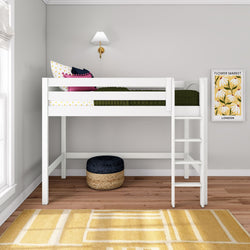 White loft twin bed with ladder in modern kids bedroom, green quilt and colorful pillows, wall sconce and framed floral art, woven pouf on hardwood floor with yellow rug