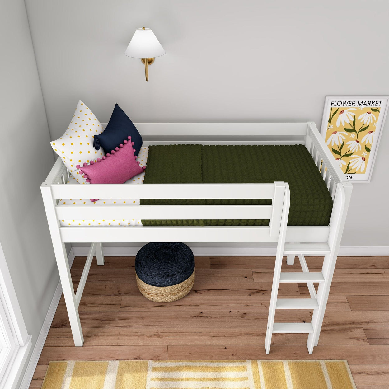 White wooden loft bed with ladder in a modern kids' bedroom, green quilted blanket, polka dot sheets, pink and navy throw pillows, "Flower Market" floral wall art and woven pouf on hardwood floor