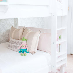 Kids' bedroom with a cozy white bed, decorative pillows, and a cute stuffed toy on a bunk bed.