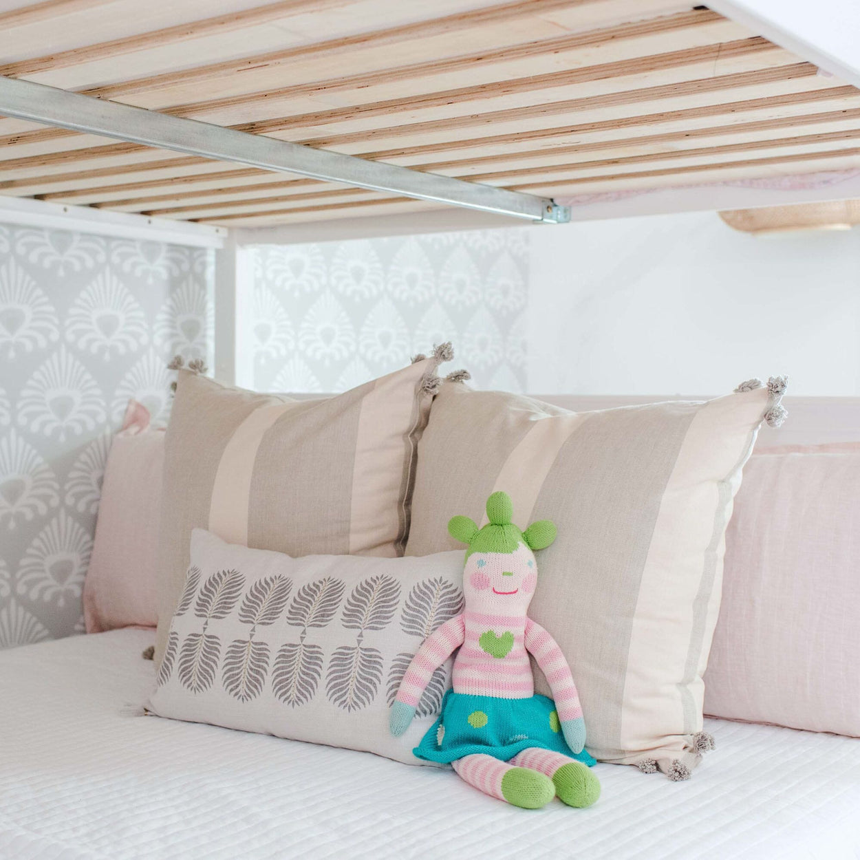 Stuffed toy on cozy children's bed with decorative pillows.