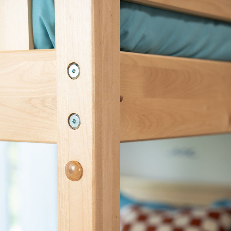Close-up of natural wood bunk bed frame with metal bolts and wooden pegs, teal mattress and blurred bedding in background