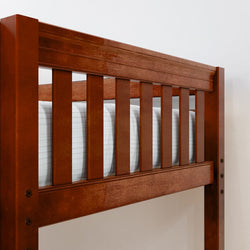 Wooden bunk bed frame with top mattress against a white wall.
