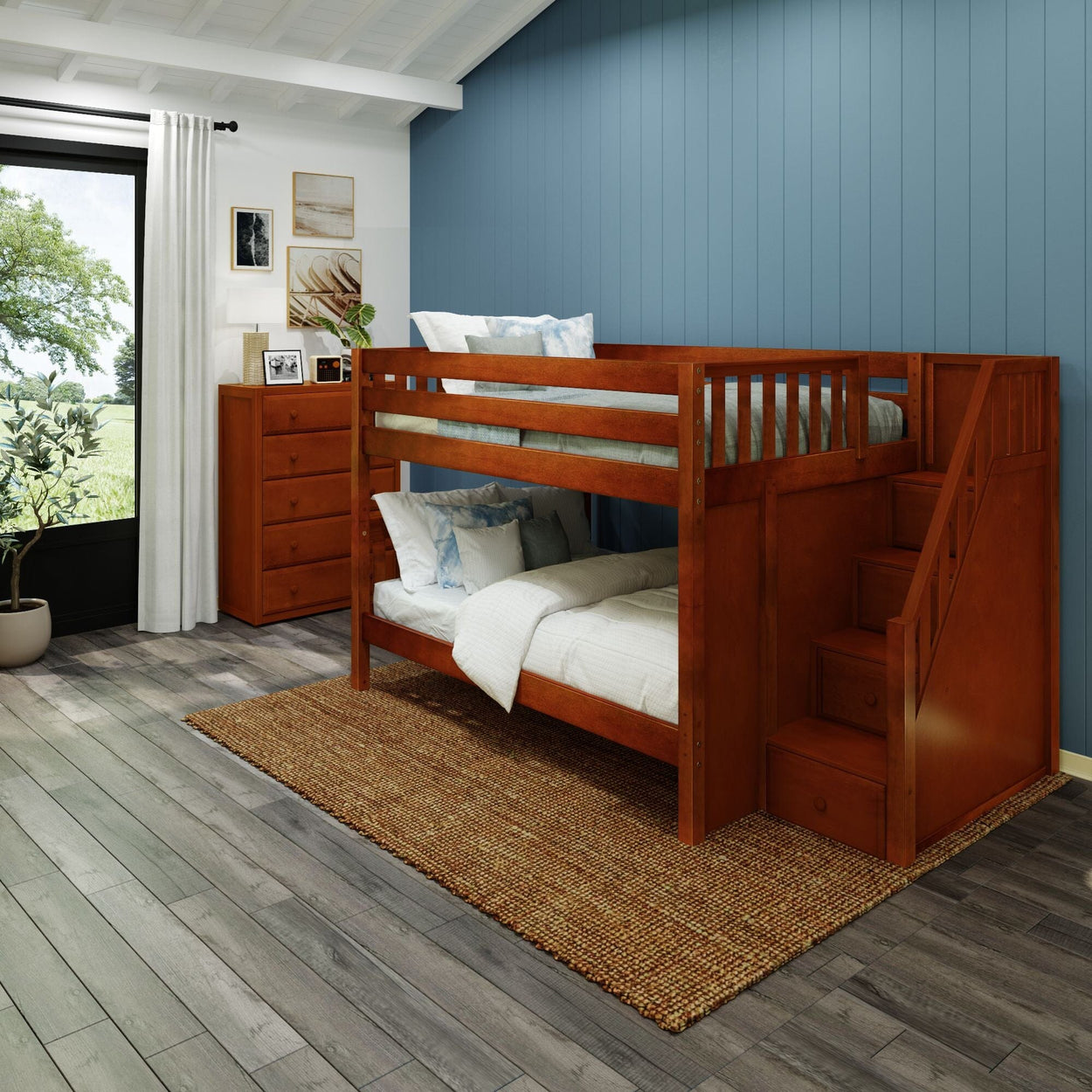 Wooden bunk bed with stairs in a cozy bedroom with blue walls, decorated with a chest of drawers and framed art.