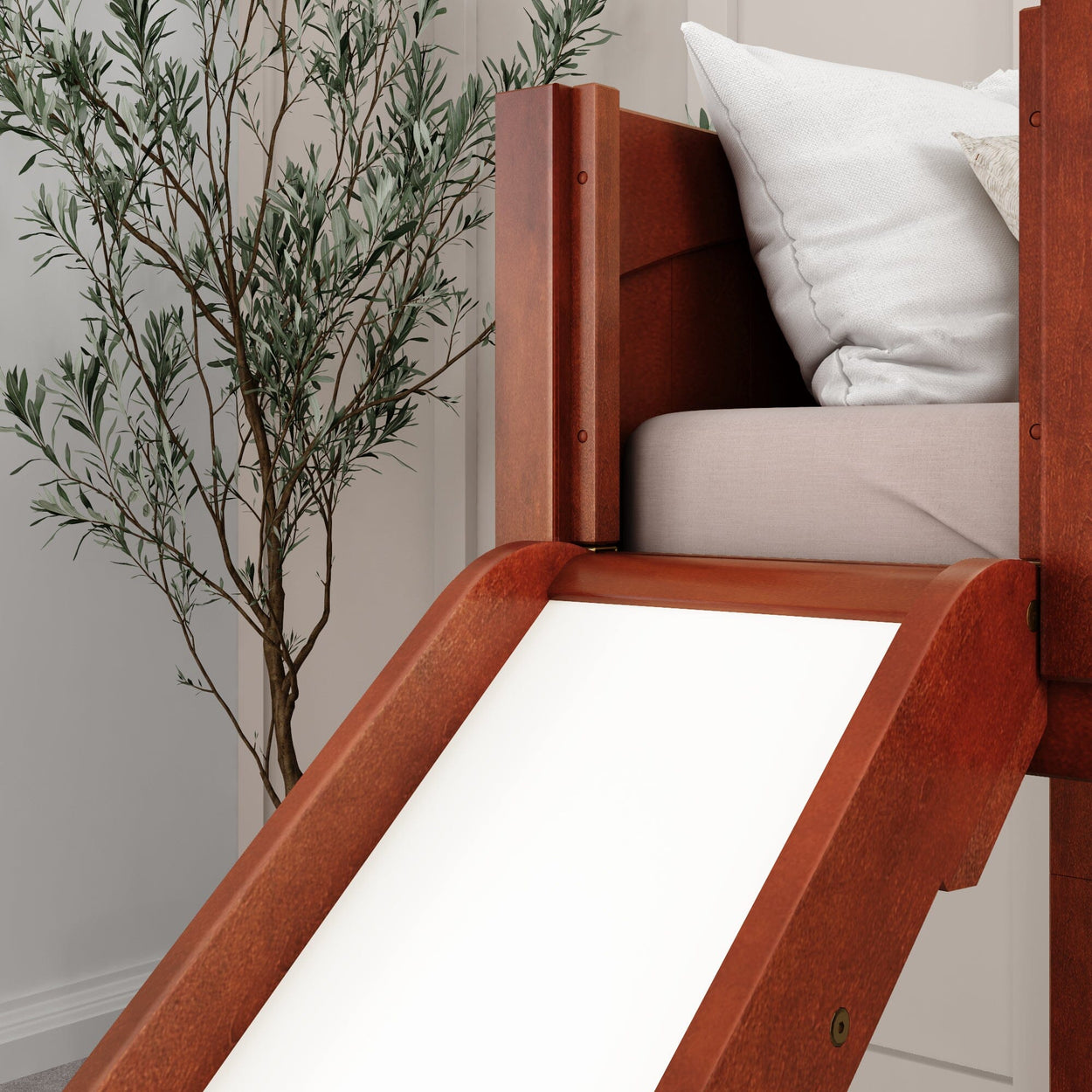 Wooden loft bed with slide and white bedding, next to a tall indoor plant in a modern bedroom setting.