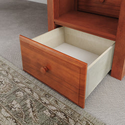Open wooden drawer on carpeted floor next to rug.