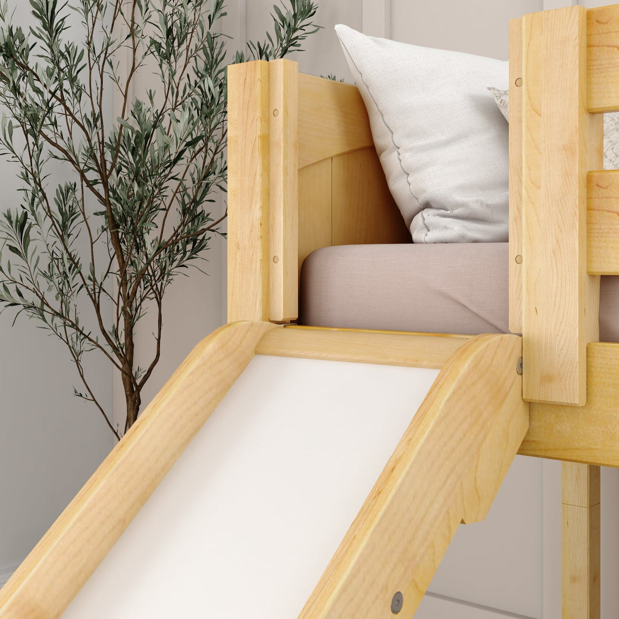 Wooden loft bed with slide and pillow in a modern bedroom with decorative plant.