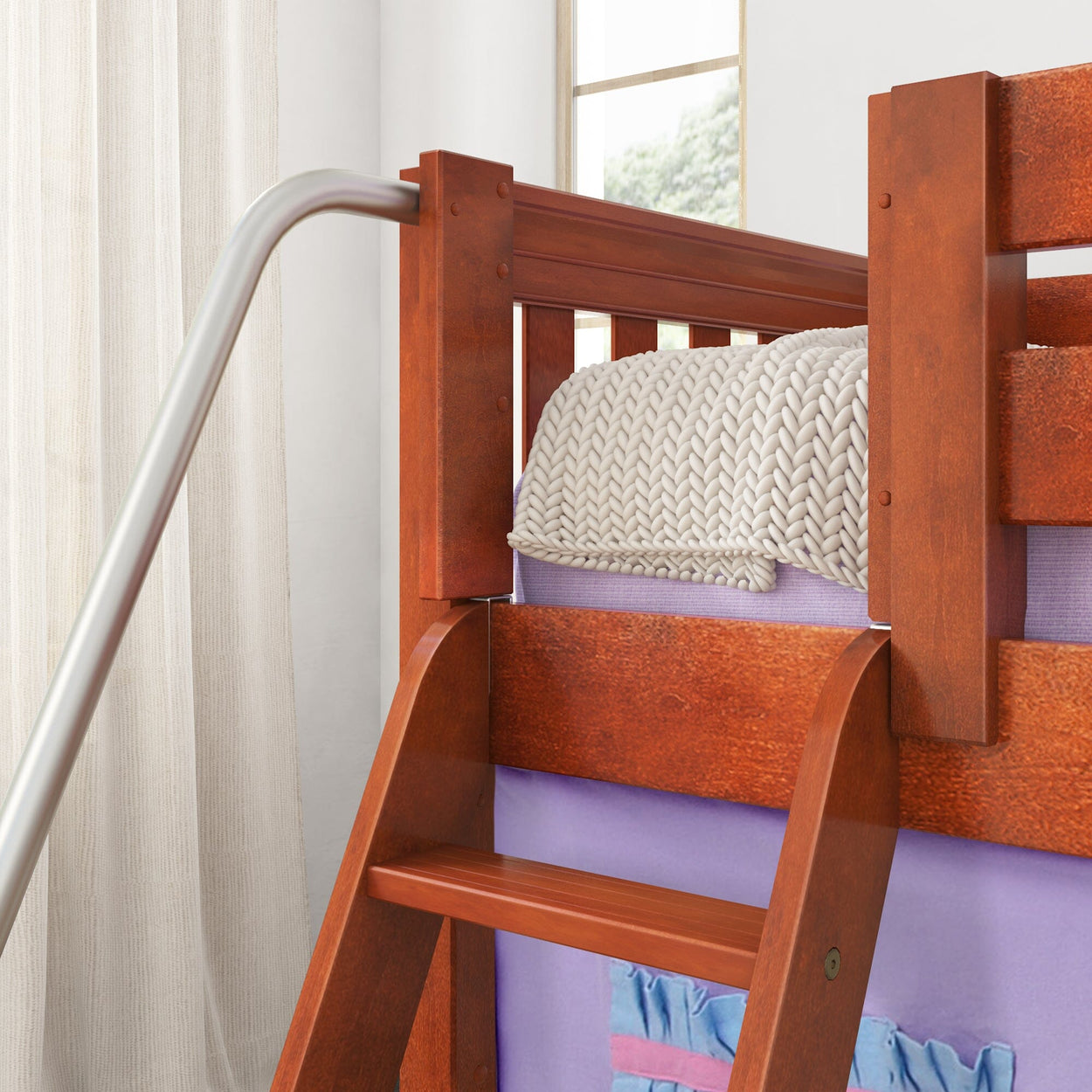 Rustic wooden bunk bed with knit blanket and metal safety rail in a bright bedroom.