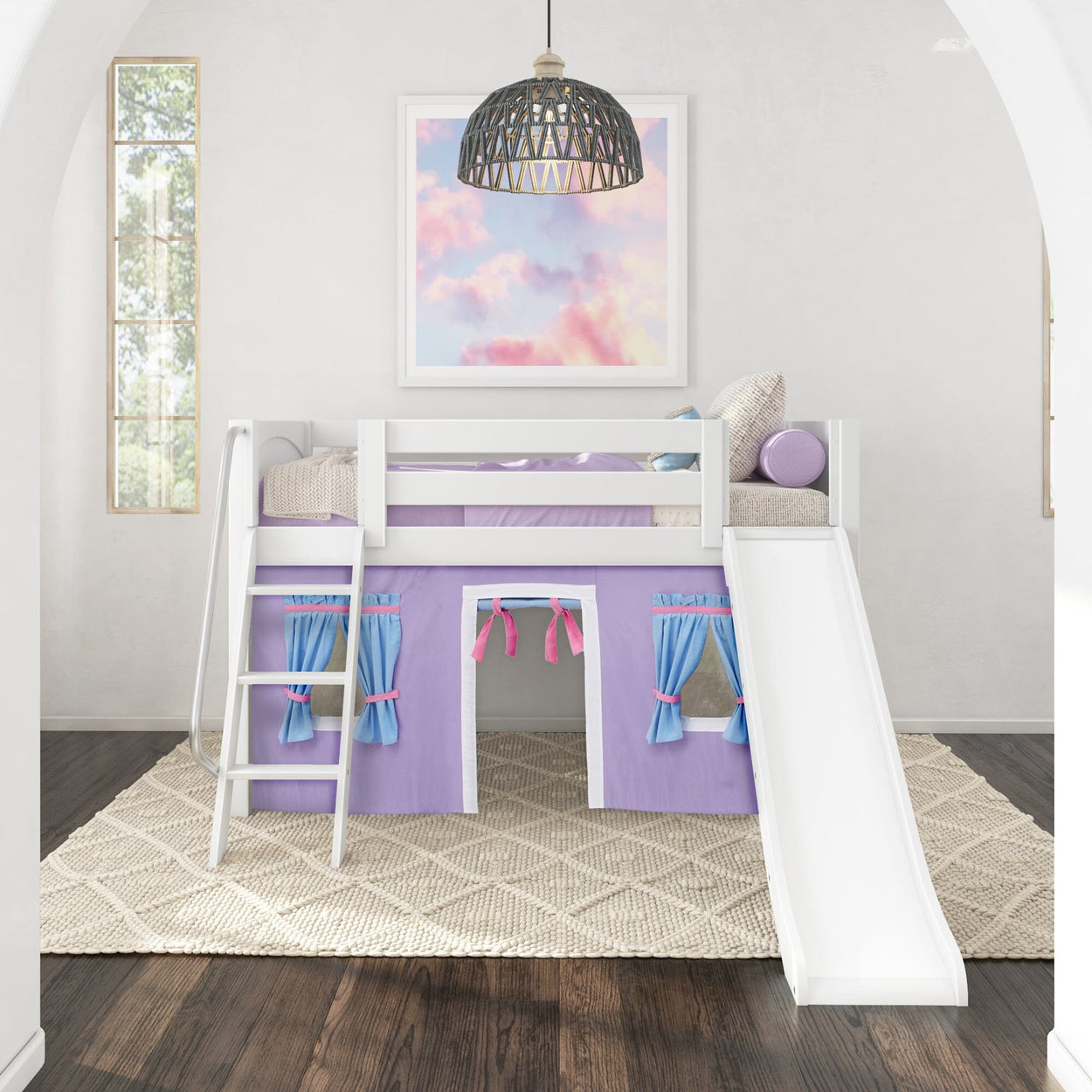 White loft bed with slide and purple curtains in a bright children's room with an art piece on the wall.
