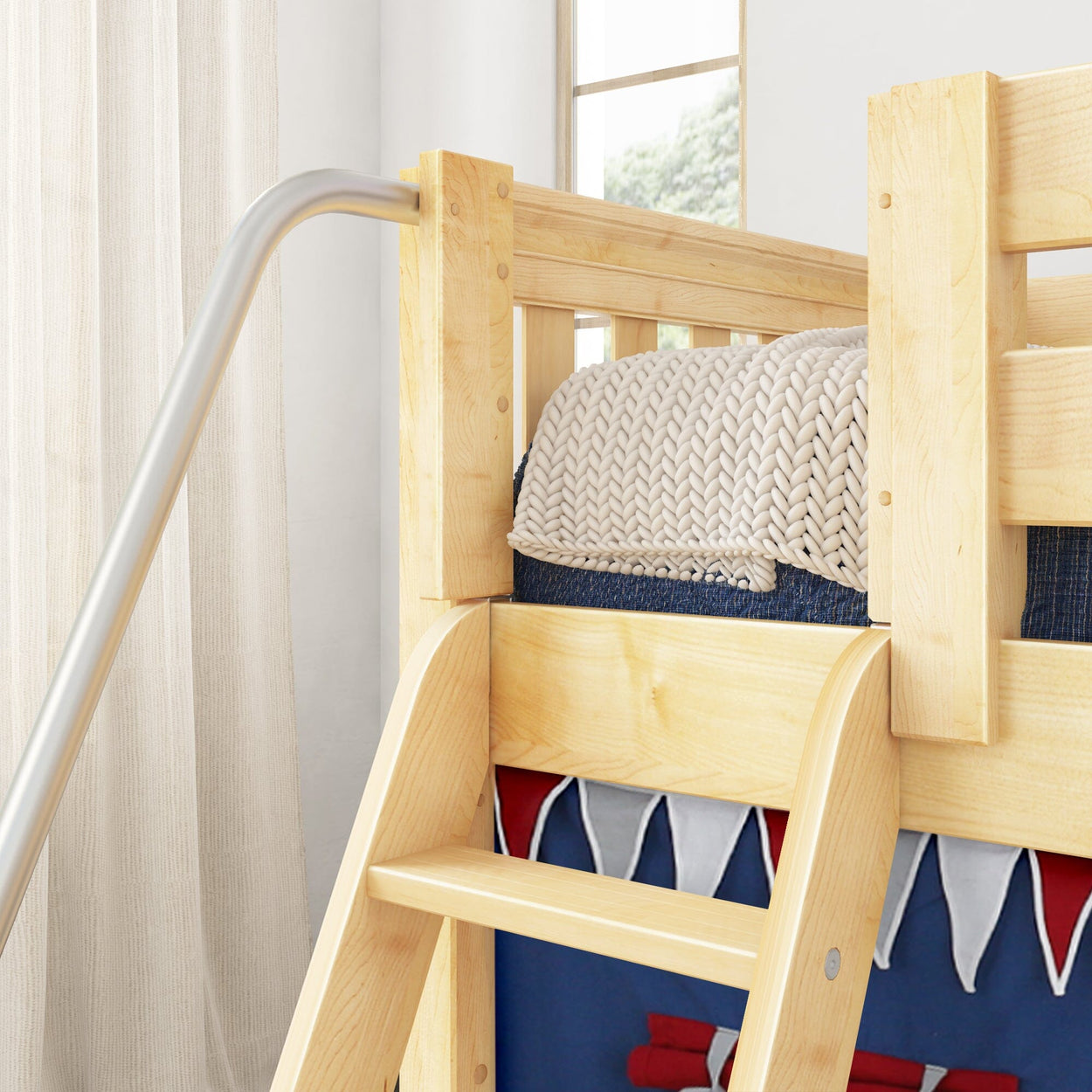 Wooden bunk bed with ladder and a cozy knit blanket in a bright bedroom with curtains and a window view.