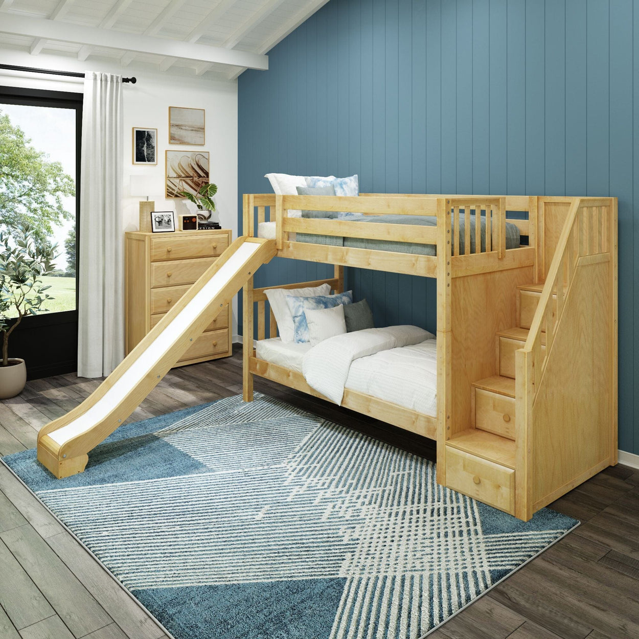 Wooden bunk bed with slide in a modern children's room with blue accent wall and geometric rug.