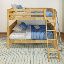 Wooden bunk bed with blue bedding and polka dot pillows on a striped rug.